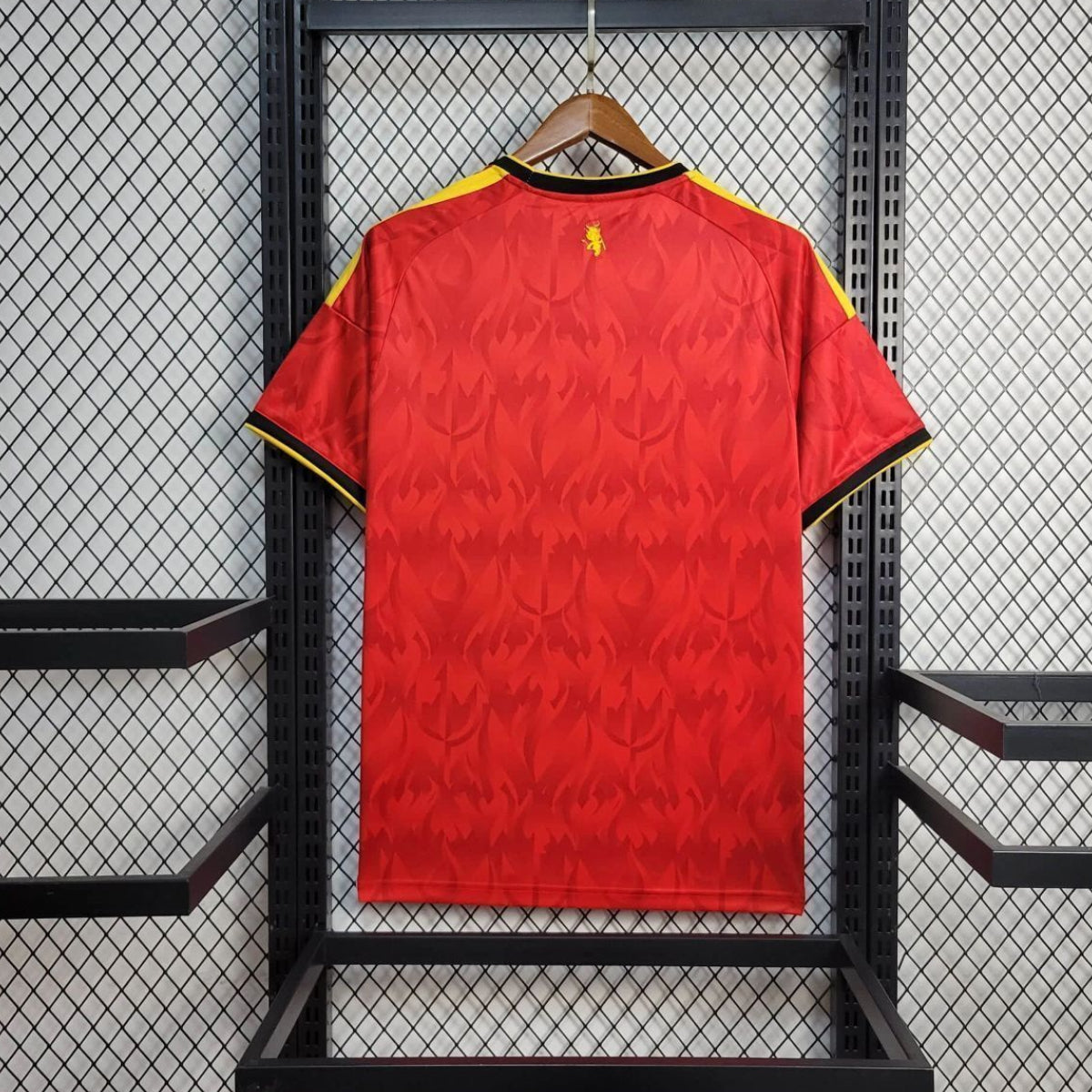 Red belgium home jersey with yellow accents on a hanger against a black metal grid background